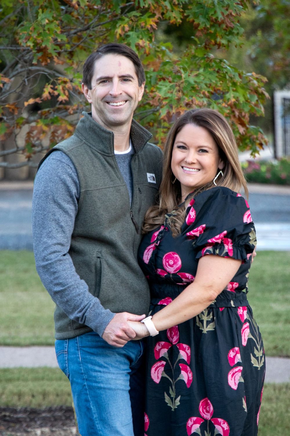 Couple holding hands and smiling under autumn leaves