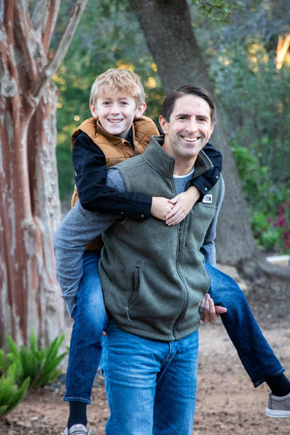 Dad giving his son a piggyback ride, both laughing